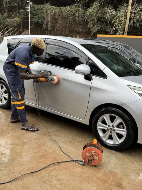 A staff member polishing a white car at the car wash